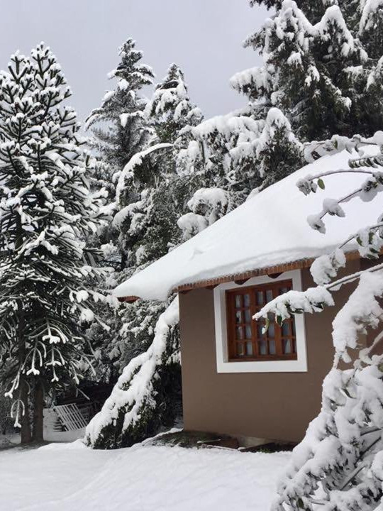 Una cabaña con el techo cargado de nieve
